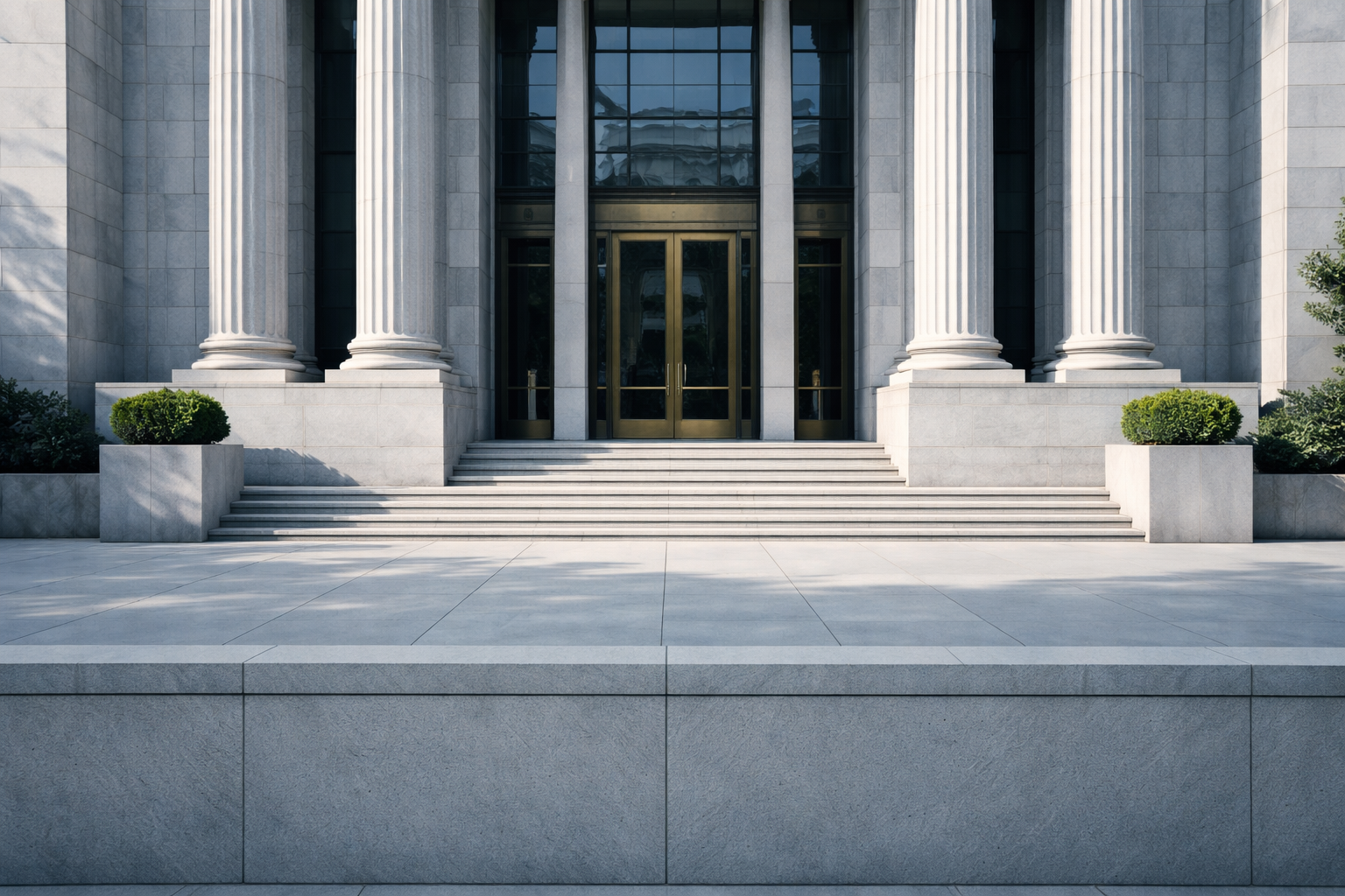 A sunlit view of the entrance colonnade or interior corridor of a federal government building, featuring classical architecture in neutral stone tones.