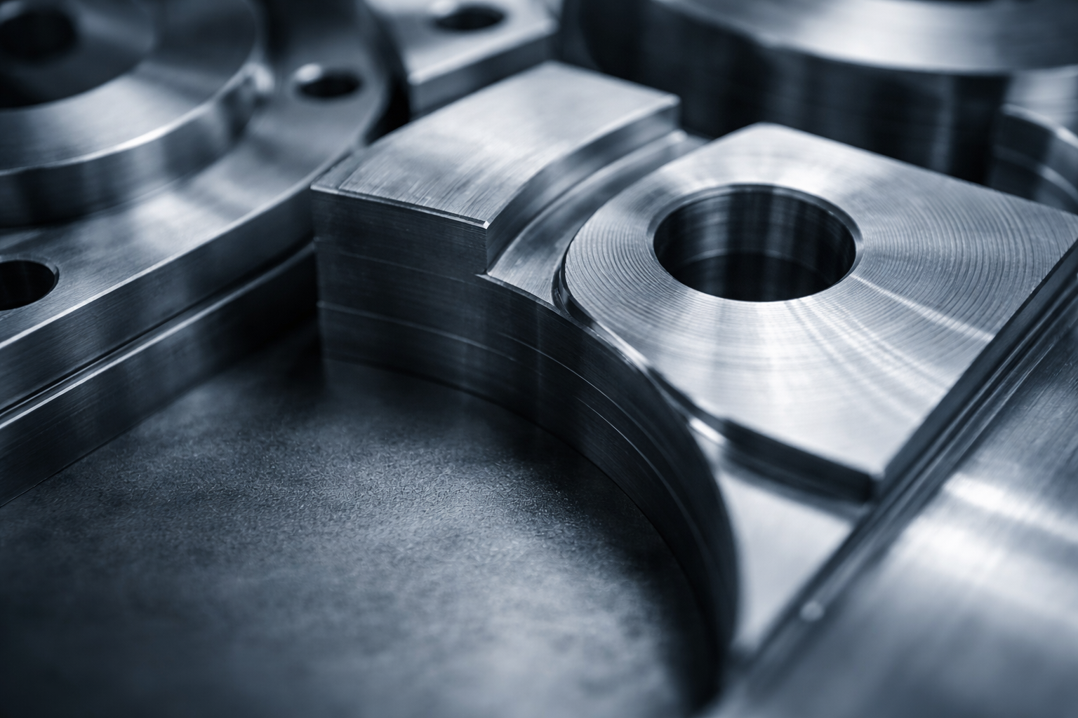 Close-up photograph of machined metal surfaces showing tooling marks and industrial texture under soft natural light.