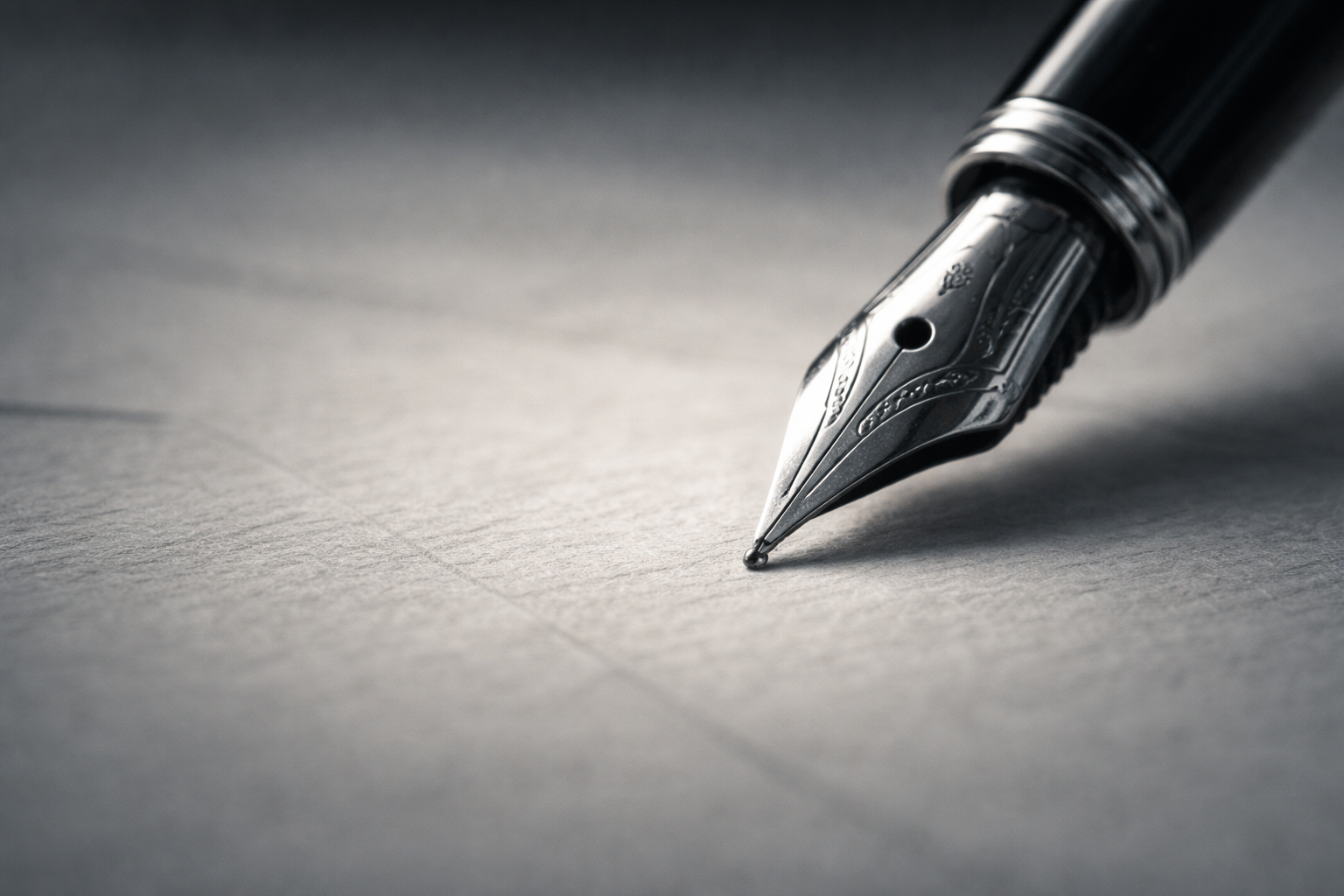 A fountain pen poised on textured paper, photographed in close-up with soft light and shallow focus.